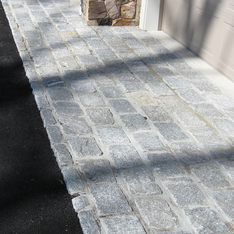 close up of cobblestone installed in front of a garage, in a driveway